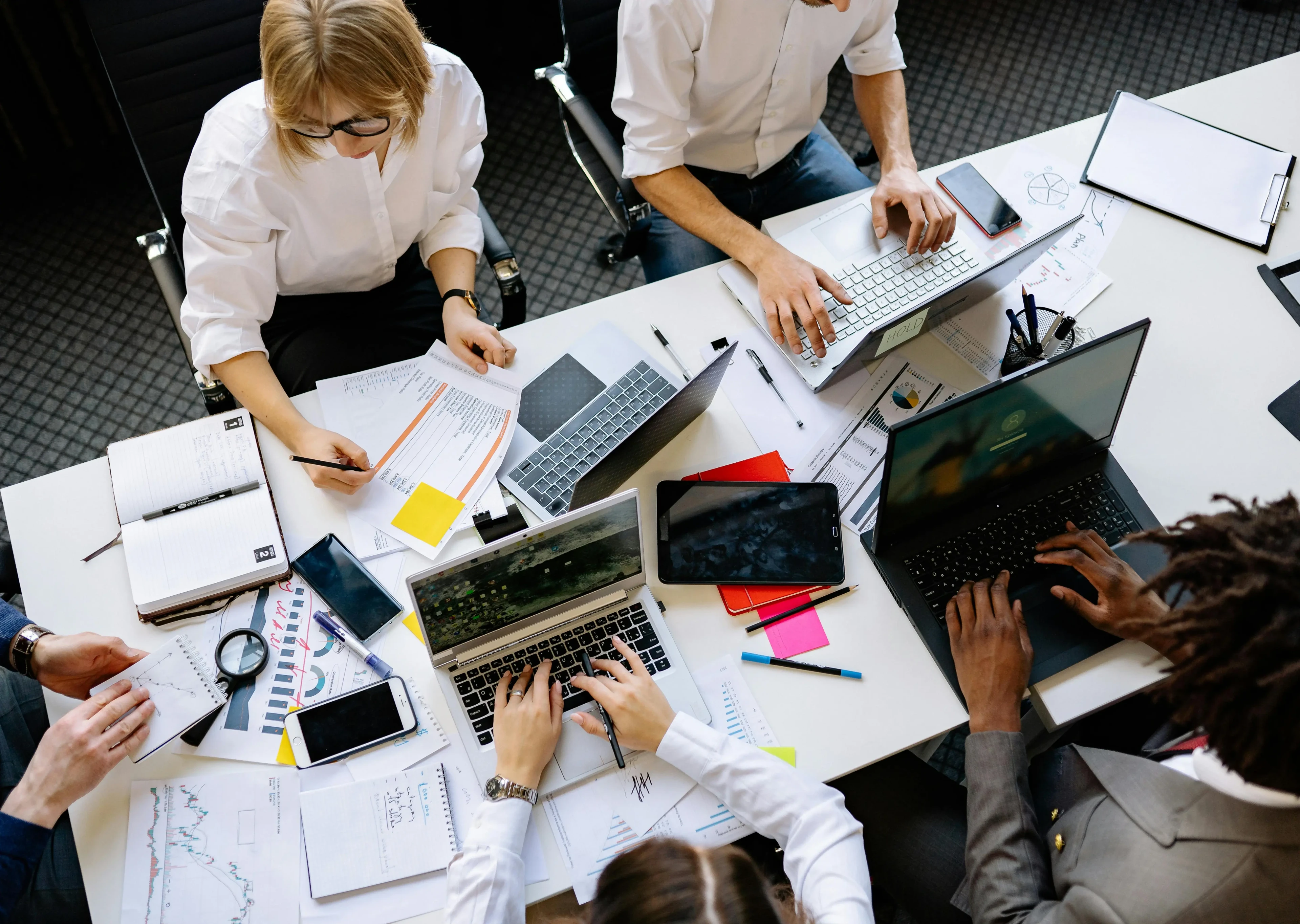 An office table busy with laptops and report papers